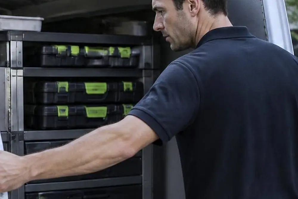 Technician at the open side of a service van with racks of parts cases
